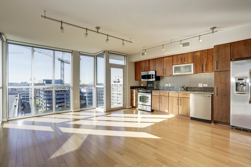 Helle, leere Wohnung mit raumhohen Fenstern und Blick über die Stadt.